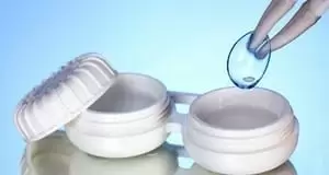 Contact lenses in containers and tweezers on blue background